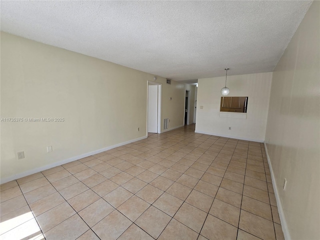 tiled empty room featuring a textured ceiling