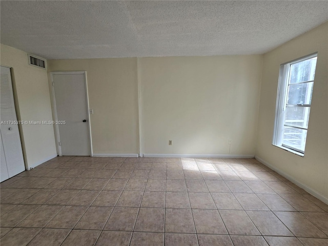 tiled spare room with a textured ceiling