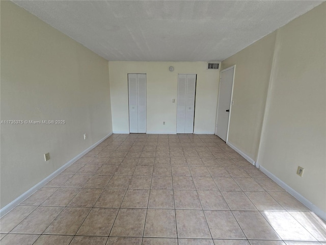 unfurnished bedroom featuring multiple closets and light tile patterned flooring