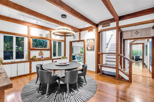 dining space with light hardwood / wood-style floors, rail lighting, and beamed ceiling