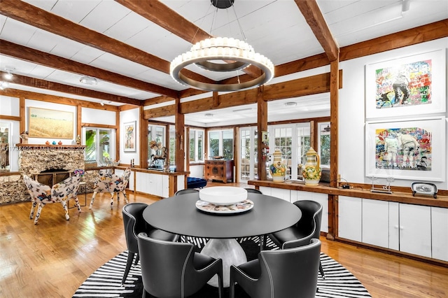 dining space featuring a fireplace, beam ceiling, and light wood-type flooring