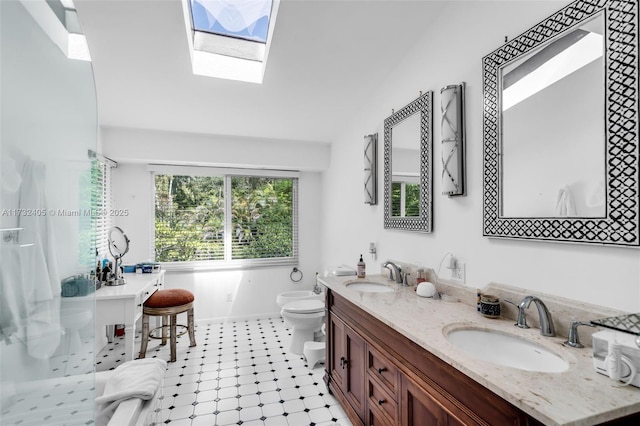 bathroom featuring vanity, vaulted ceiling with skylight, and toilet