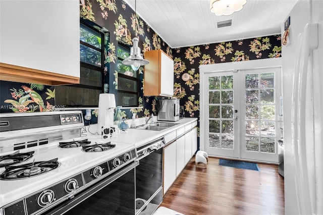 kitchen with french doors, dark wood-type flooring, range with gas stovetop, dishwasher, and white cabinets