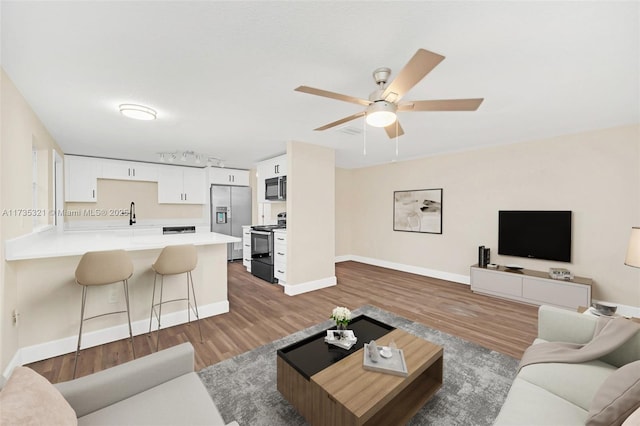 living room with rail lighting, dark wood-type flooring, and ceiling fan