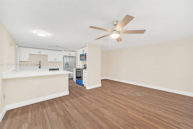 kitchen with ceiling fan, appliances with stainless steel finishes, white cabinetry, wood-type flooring, and kitchen peninsula