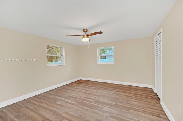 spare room with ceiling fan, a wealth of natural light, and light wood-type flooring