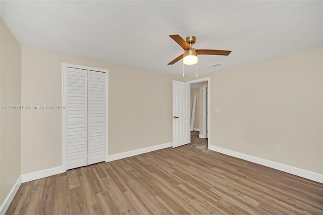 unfurnished bedroom featuring a textured ceiling, a closet, ceiling fan, and light wood-type flooring