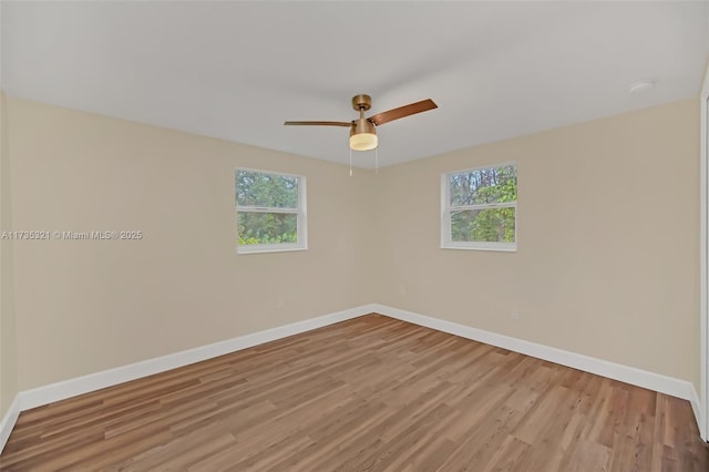 empty room with ceiling fan, plenty of natural light, and light hardwood / wood-style flooring