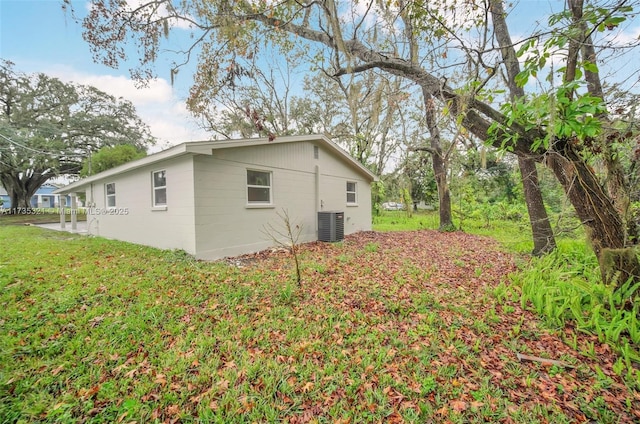 view of side of property featuring cooling unit and a yard