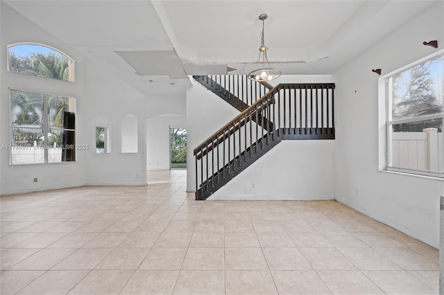 interior space with an inviting chandelier, a towering ceiling, and light tile patterned floors