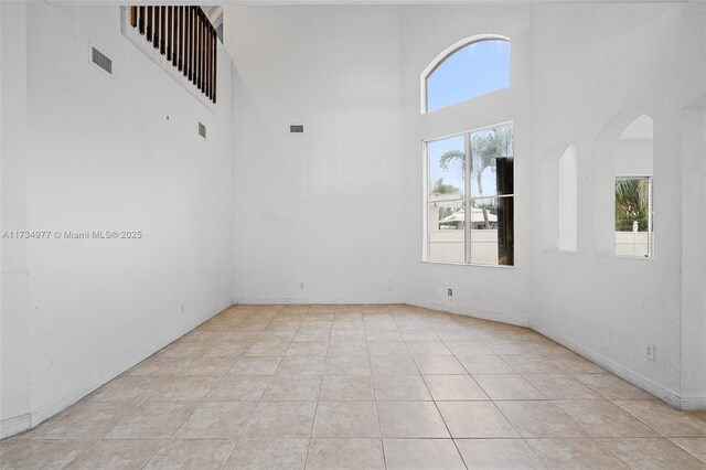 tiled empty room featuring a high ceiling