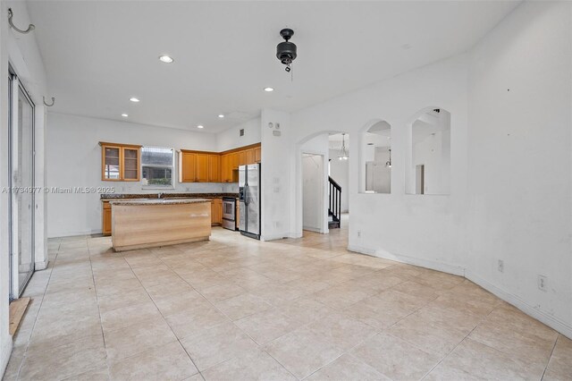 kitchen with sink, stainless steel appliances, a center island, and stone counters