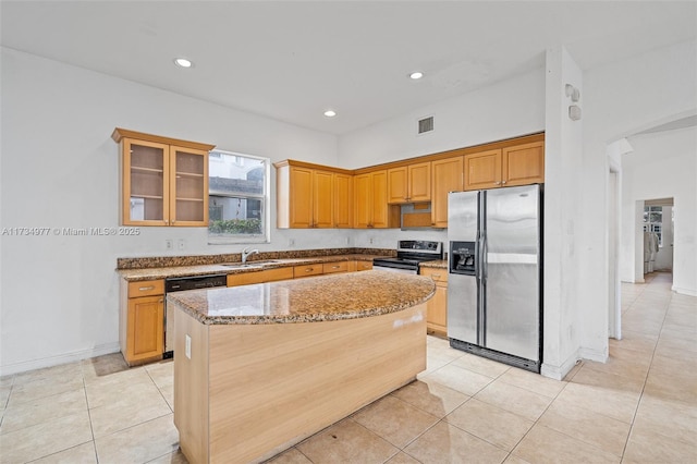 kitchen with sink, a center island, light tile patterned floors, stainless steel appliances, and light stone countertops