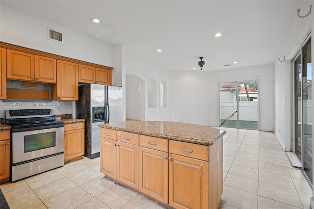 kitchen with light stone counters, stainless steel appliances, a kitchen island, and light tile patterned floors