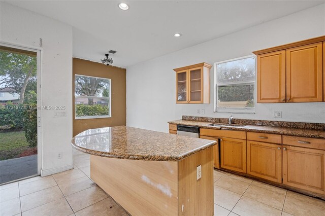 kitchen featuring sink, dishwasher, a kitchen island, light stone counters, and light tile patterned flooring