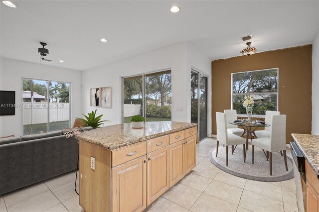 kitchen featuring dishwasher, a kitchen island, plenty of natural light, and light stone counters