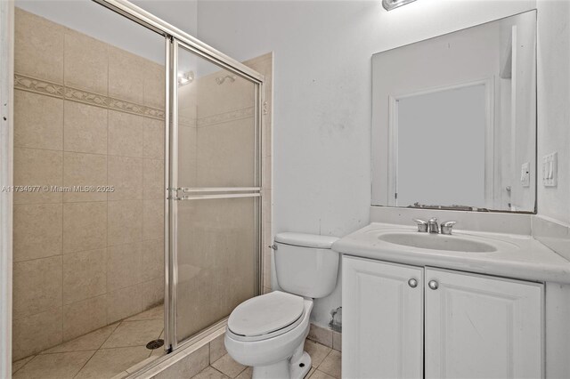 bathroom featuring tile patterned floors, vanity, toilet, and a shower with shower door