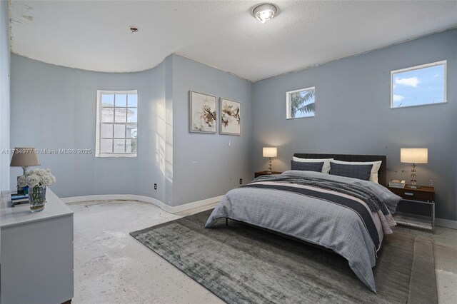 bedroom with a textured ceiling, multiple windows, and concrete floors