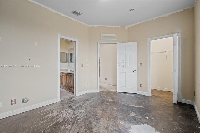 unfurnished bedroom featuring a walk in closet, ensuite bathroom, and a closet