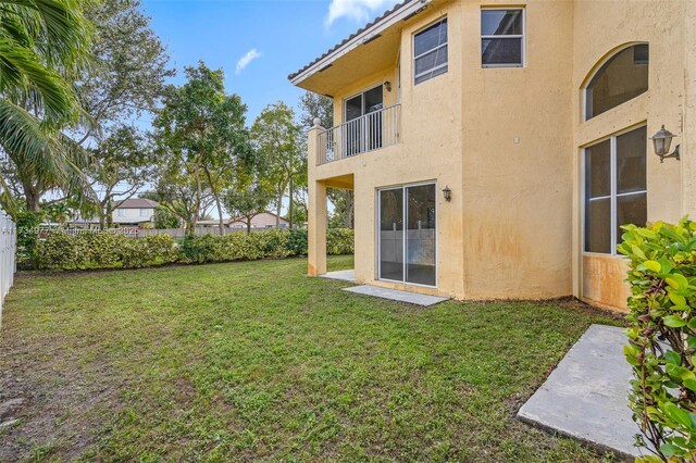 rear view of house with a balcony and a yard