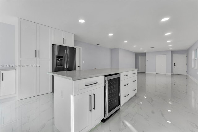 kitchen featuring white cabinets, stainless steel refrigerator with ice dispenser, a center island, and beverage cooler