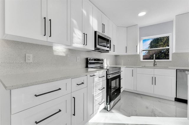 kitchen with sink, decorative backsplash, stainless steel appliances, and white cabinets