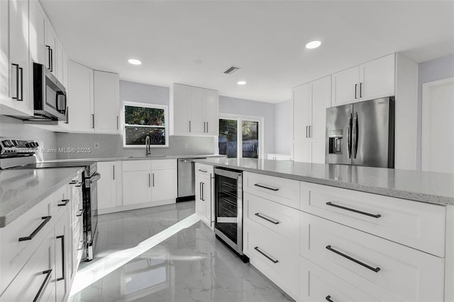 kitchen featuring wine cooler, sink, white cabinetry, tasteful backsplash, and stainless steel appliances