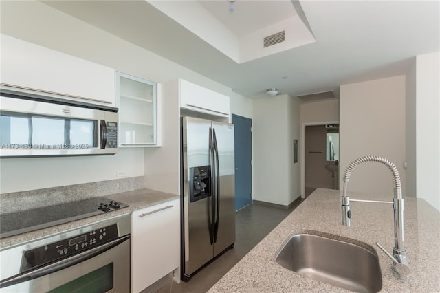 kitchen featuring sink, light stone countertops, white cabinets, and appliances with stainless steel finishes