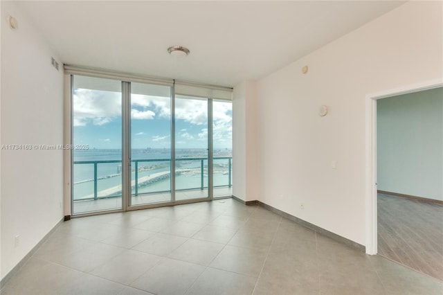 tiled spare room featuring expansive windows and a water view