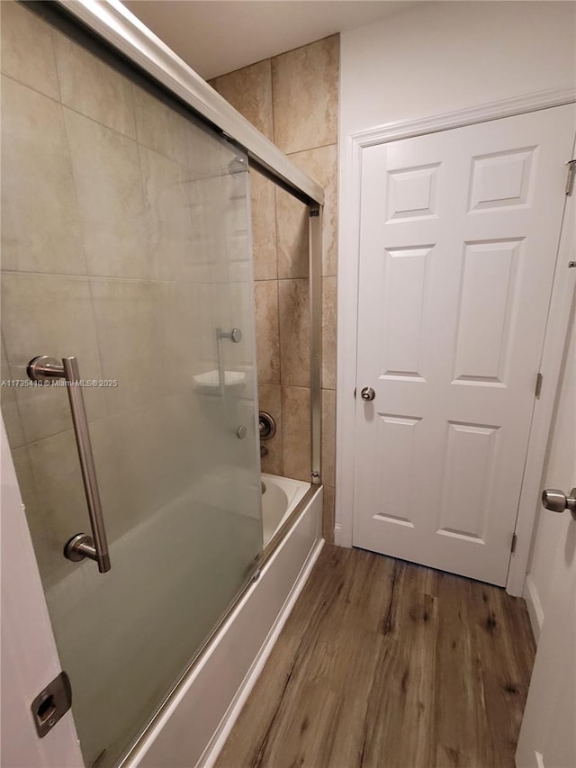 full bath with shower / bath combination with glass door and wood finished floors