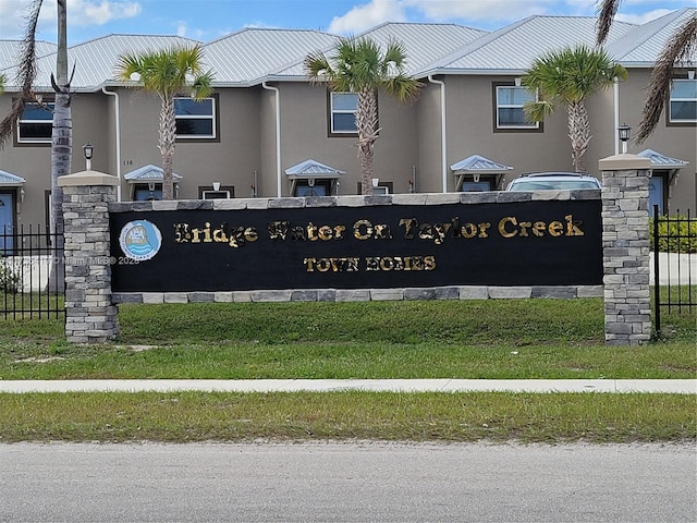 community sign with fence and a lawn