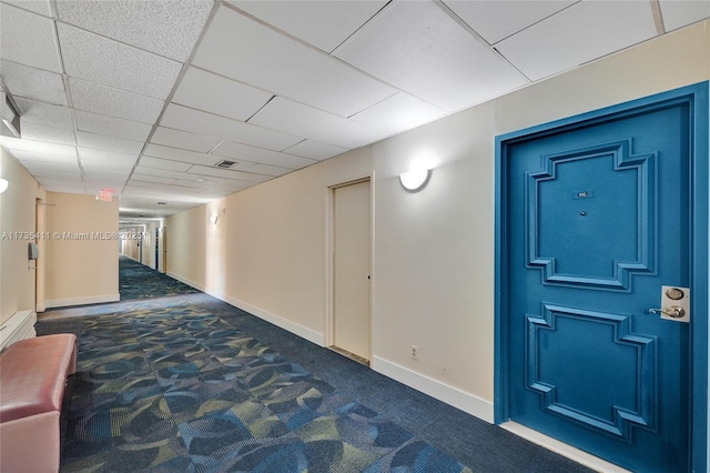 corridor with a drop ceiling and dark carpet