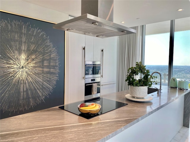 kitchen featuring double oven, sink, white cabinets, island exhaust hood, and black electric stovetop