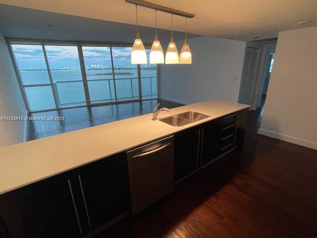 kitchen featuring sink, a water view, decorative light fixtures, dark hardwood / wood-style floors, and dishwasher