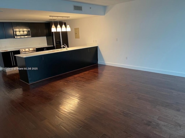 interior space with dark wood-type flooring, stainless steel appliances, sink, and hanging light fixtures