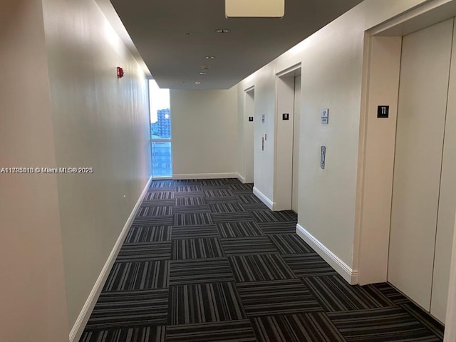 hall featuring elevator and dark colored carpet