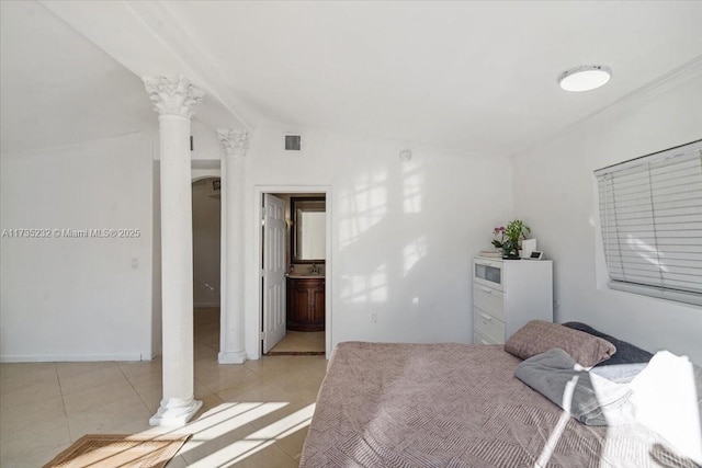 tiled bedroom featuring lofted ceiling, connected bathroom, and ornate columns