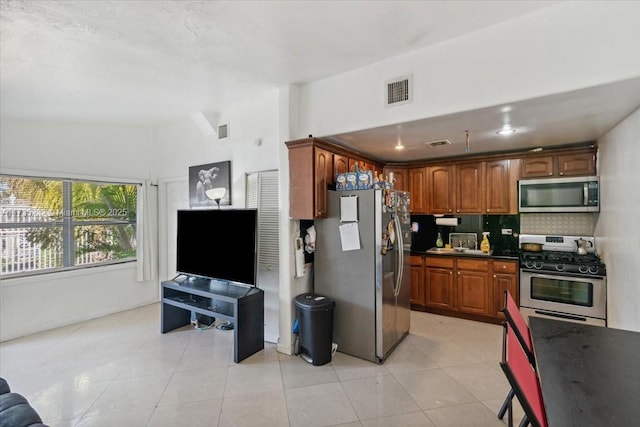 kitchen featuring decorative backsplash, light tile patterned flooring, and appliances with stainless steel finishes