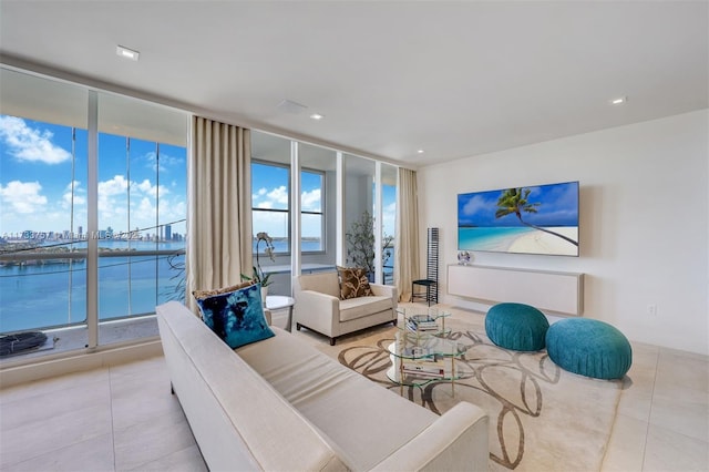 living room with expansive windows, a water view, and light tile patterned floors