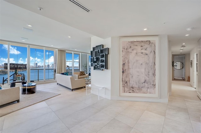 tiled living room featuring floor to ceiling windows and a water view