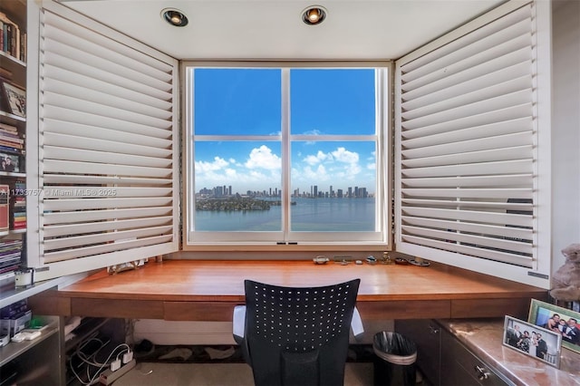 home office with a water view, plenty of natural light, and built in desk