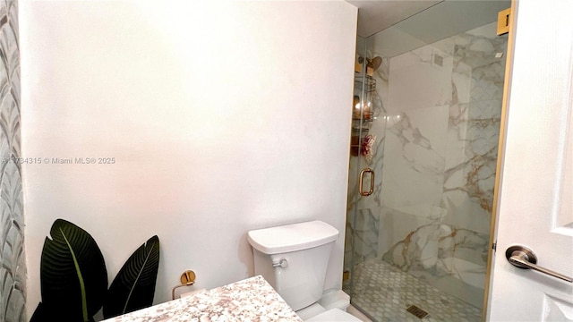 bathroom with a shower with door, vanity, and toilet