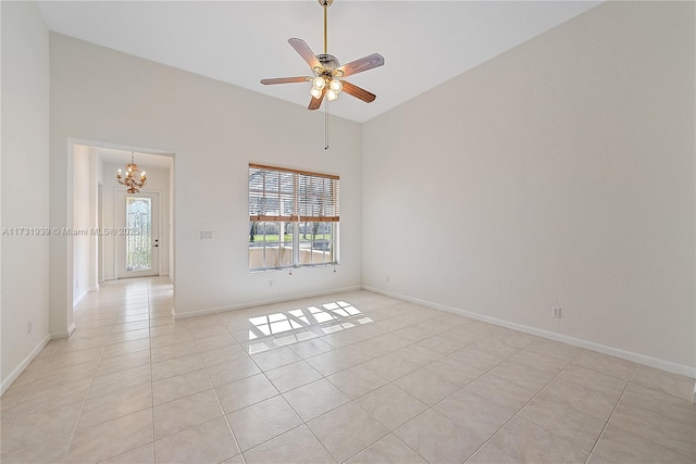 tiled empty room with a high ceiling and ceiling fan with notable chandelier