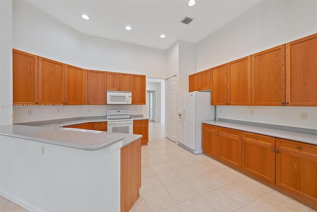 kitchen with light tile patterned flooring, sink, a high ceiling, kitchen peninsula, and white appliances