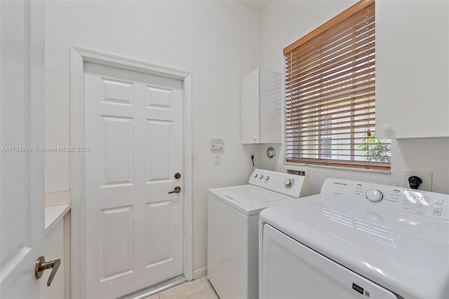 laundry area featuring light tile patterned flooring, cabinets, and washer and clothes dryer