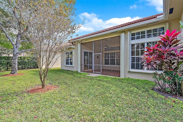 rear view of house featuring a lawn and a sunroom