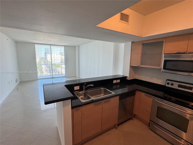 kitchen featuring sink, light tile patterned flooring, kitchen peninsula, and appliances with stainless steel finishes