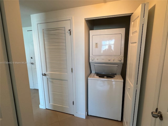 laundry area with stacked washer and clothes dryer and light tile patterned floors