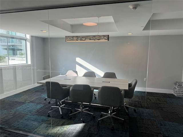 carpeted dining area with a raised ceiling