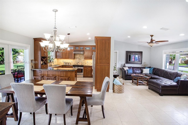 dining space featuring vaulted ceiling, ceiling fan with notable chandelier, and a wealth of natural light